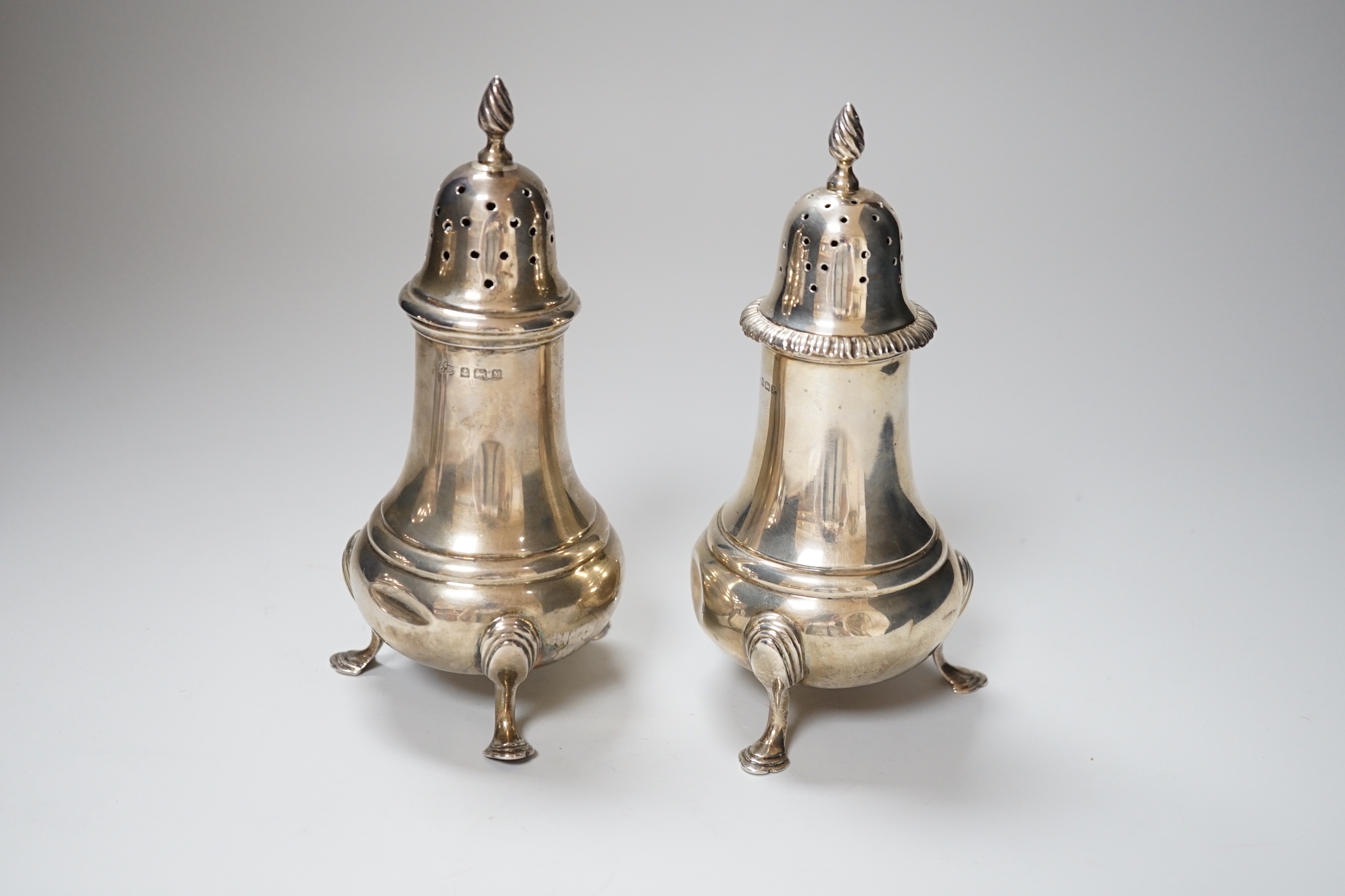 A near pair of George VI silver casters, with baluster bodies and pad feet, makers Elkington & Co, Birmingham 1936 and 1939, 16cm, 366 grams